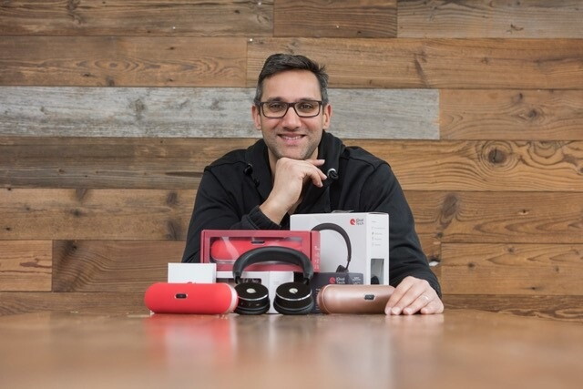 Zamir Cajee, Founder of iQualTech, sitting at a table with his products on front of him.