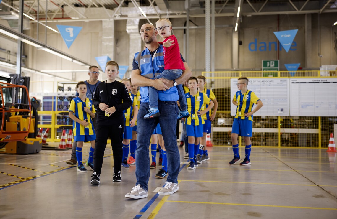 Amazon Star Enrico mit den Fußballkids, die er trainiert, im Sortierzentrum.