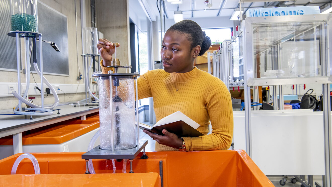 Female engineer wearing yellow jumper and studying liquid 