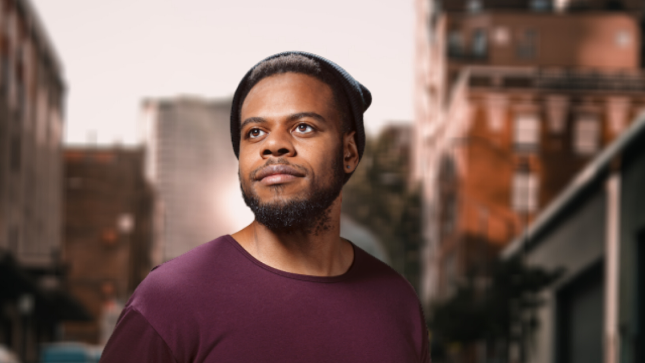 An image of a man looking off into the distance for a headshot. Behind him is a city landscape.