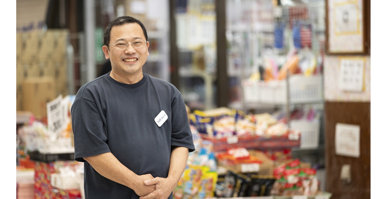 色とりどりの商品がならぶ店舗前で笑顔の仲村さん
