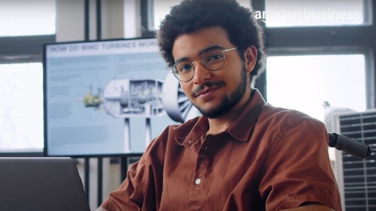 Young professional in brown shirt at modern workplace with renewable energy visuals