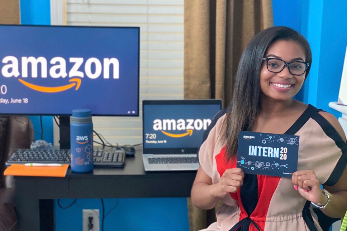 A woman sits in front of a desk. She holds a card that says "Amazon intern 2020."