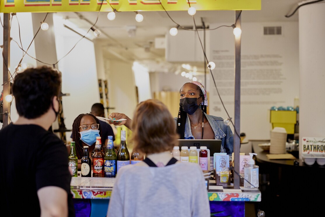 An image of a woman handing a receipt to a man across the counter of a restaurant.