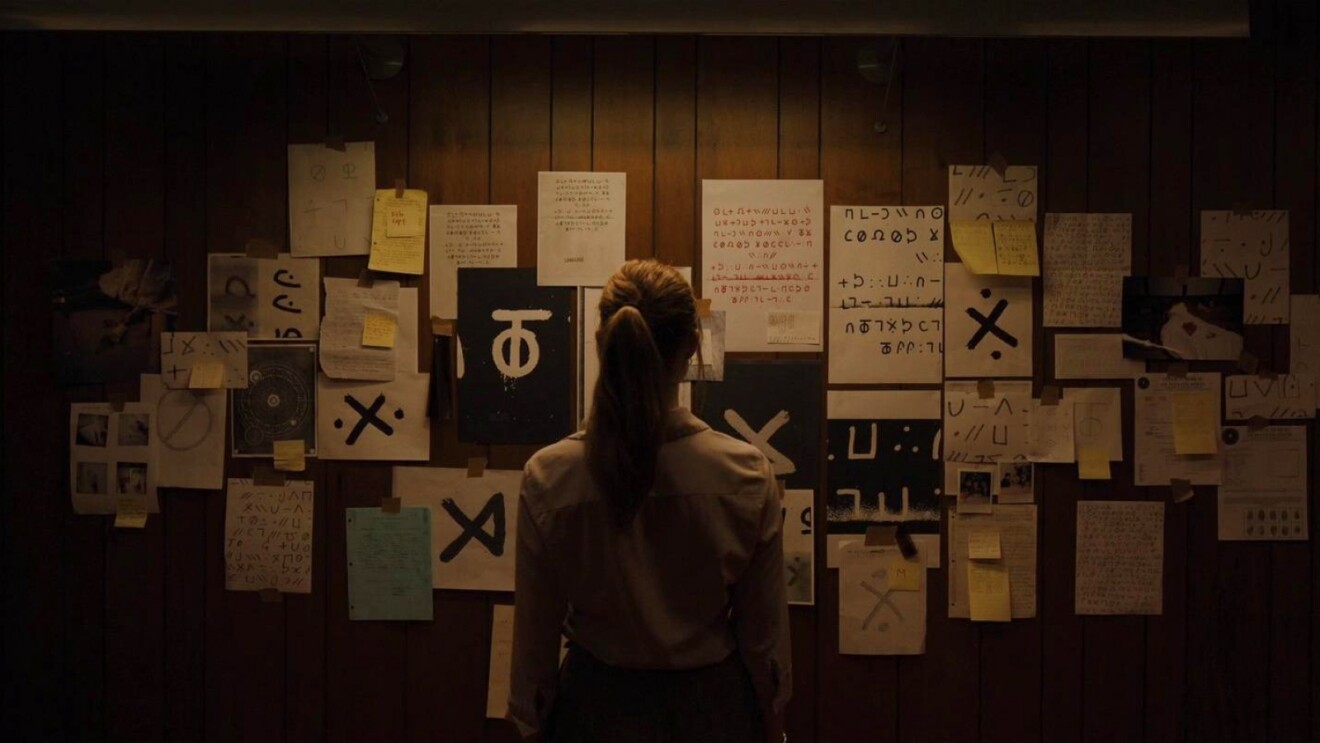 Investigator pondering wall covered in mysterious writings and symbols