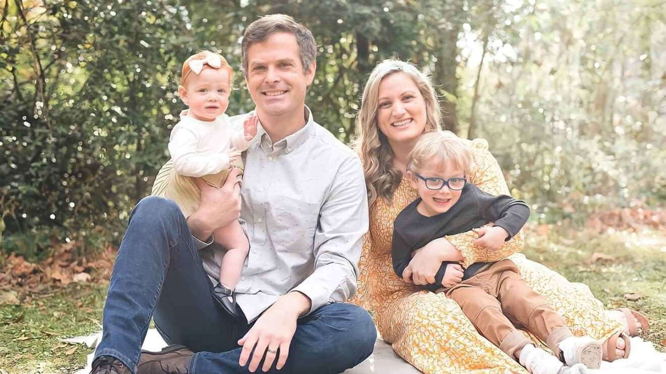 An image of a family sitting for a photo outside in a green area.