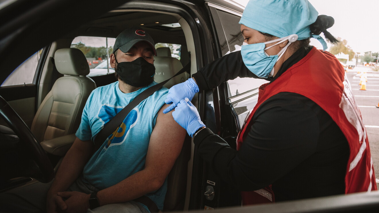 A man receives a COVID-19 vaccination while seated in his car at a drive-up vaccine clinic for Amazon Pharmacy employees. 