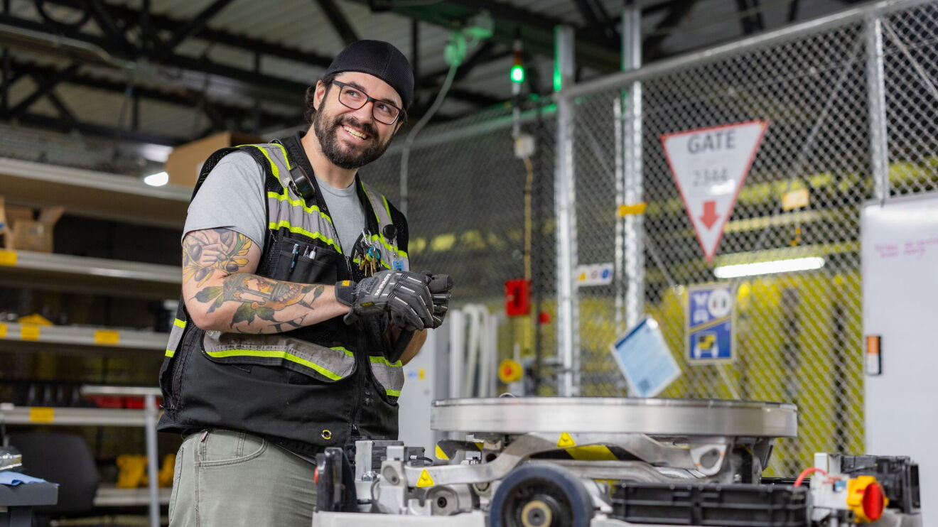Amazon employee in a robotics fulfillment center works on a robot