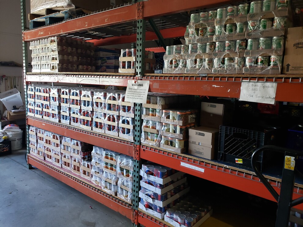 Shelves in a stockroom with food donations on them.