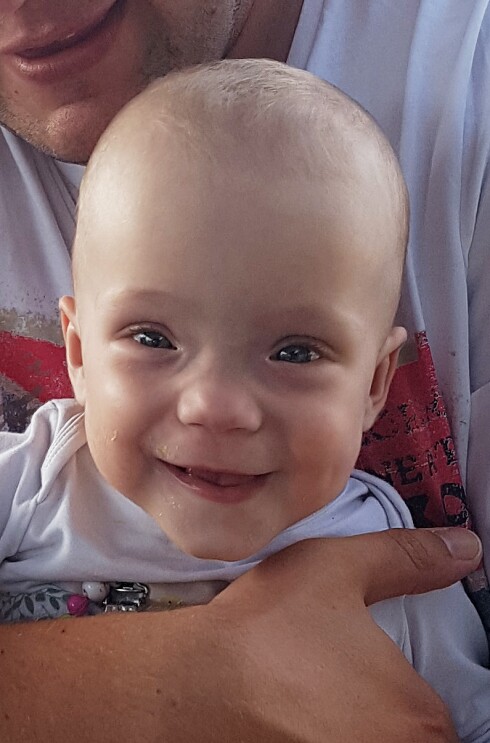 Lena ist ein kleines Baby. Sie hat große Augen und lacht in die Kamera.