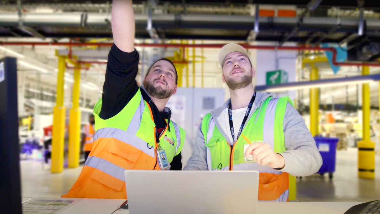 Dennis mit Kolleginnen und Kollegen an seinem Arbeitsort, dem Amazon Logistikzentrum in Oelde.