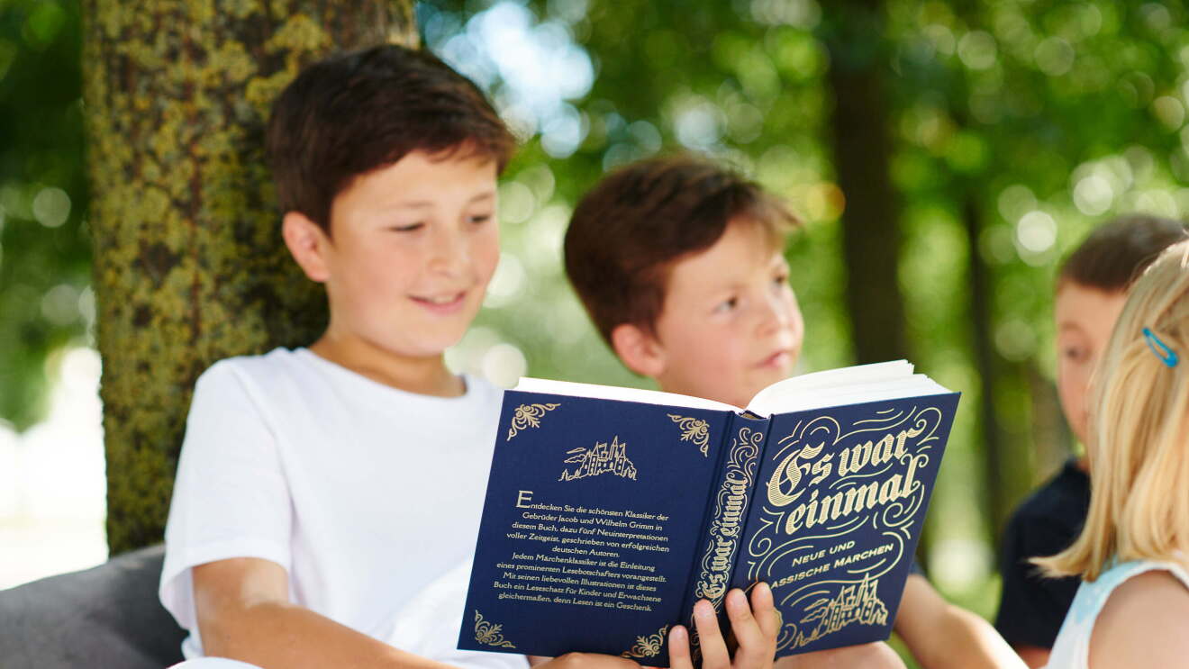 Kind liest aus Märchenbuch "Es war einmal"