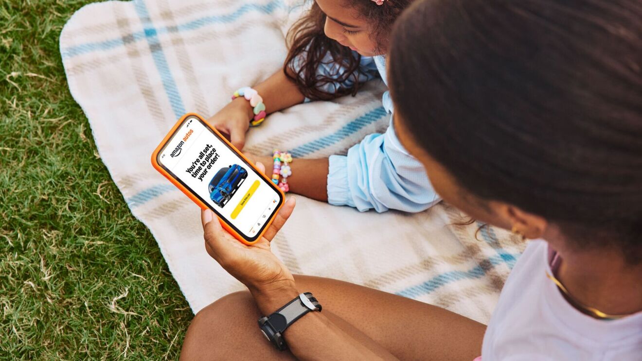 Friends relaxing on blanket, viewing smartphone with Amazon app