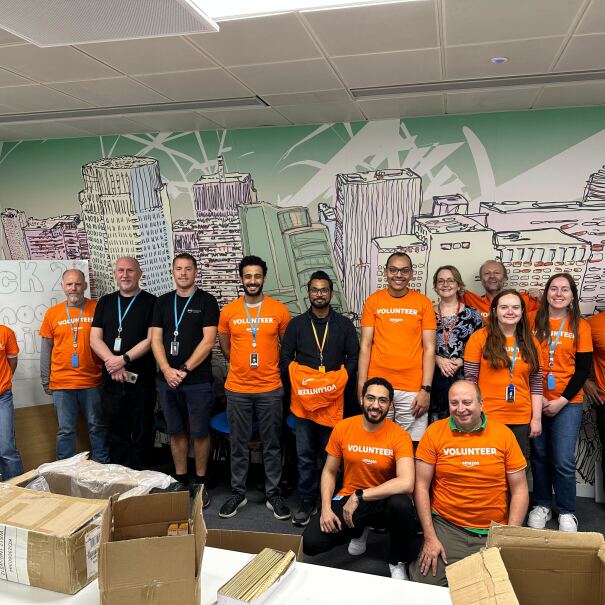 A group of Amazon employees take a break from packing back to school backpacks for children