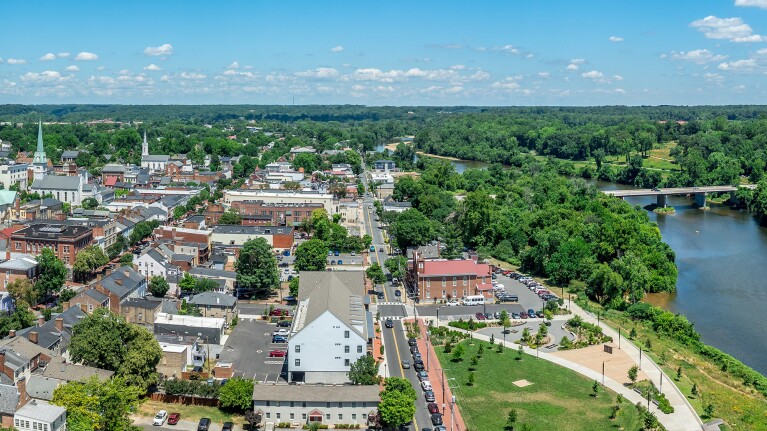 Aerial view of a town in Virginia with a historic bridge spanning a river with a small town and green trees along the waterfront.