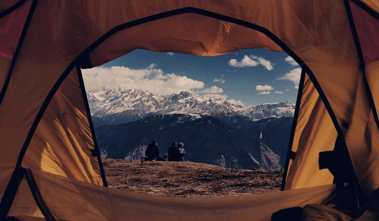 A views from a camp tent shows 2 trekkers relaxing
