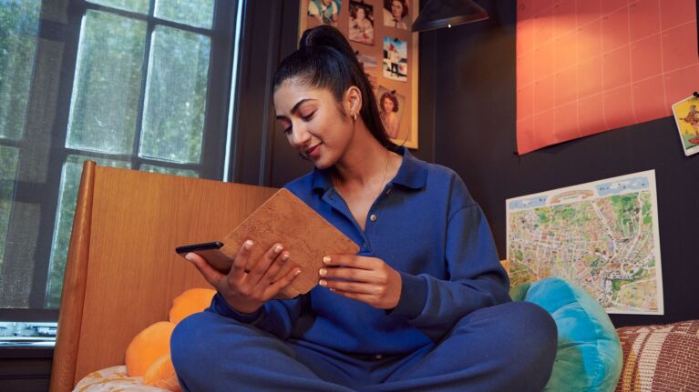 Woman holding Kindle in cozy room with map and photos on wall