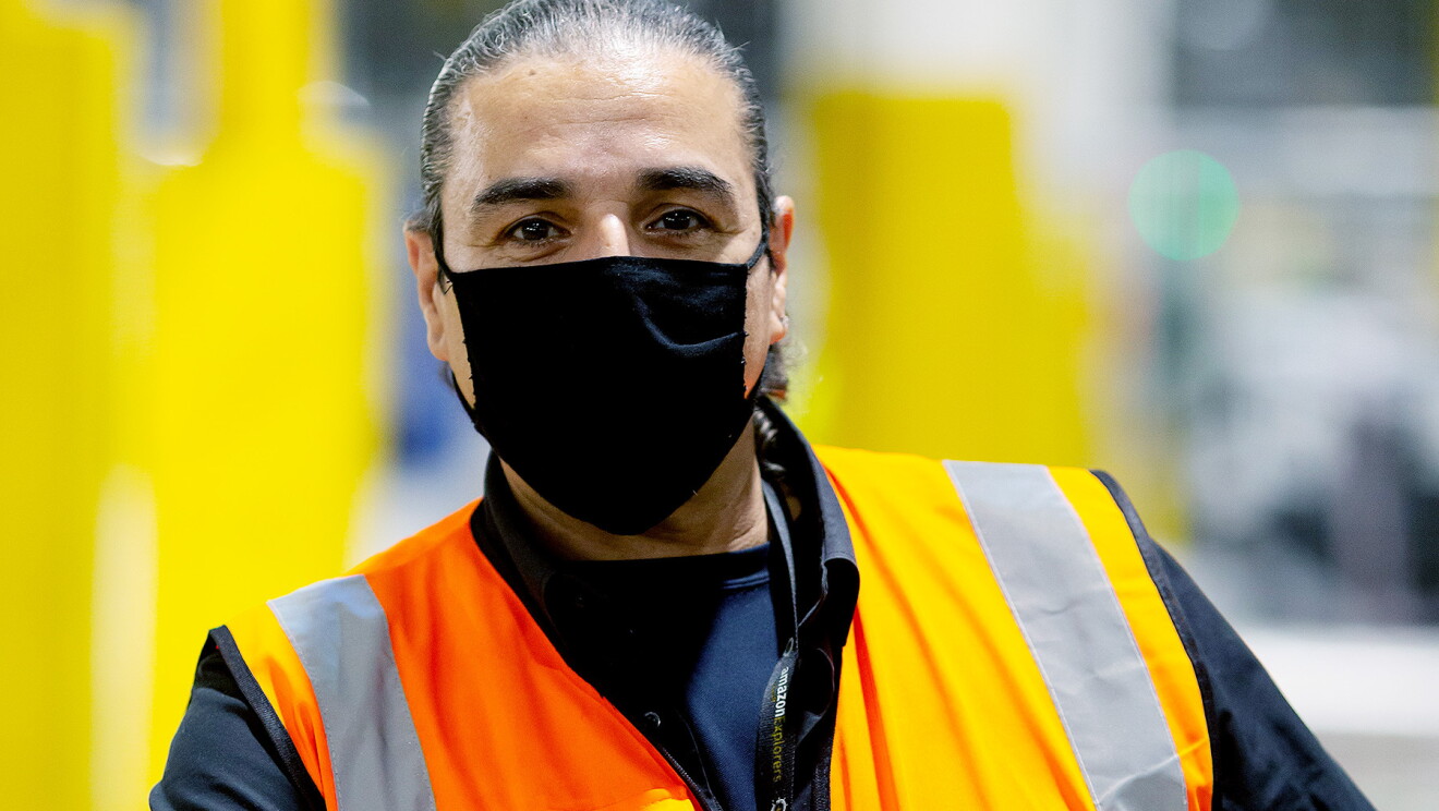 Antonio Kanaris - wearing a facemask and hi-vis in a fulfilment centre.