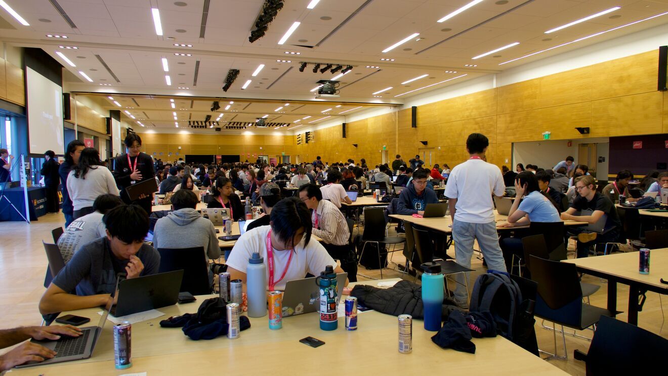 Students working on computers in busy communal workspace