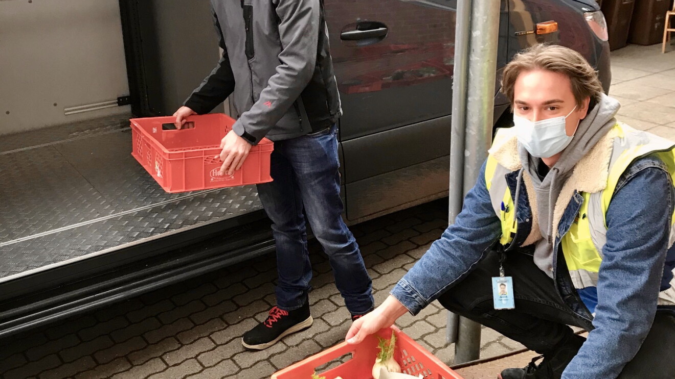 Ein Amazon Mitarbeiter belädt gemeinsam mit einem Tafel-Helfer das Lieferfahrzeug. Beide tragen Masken.