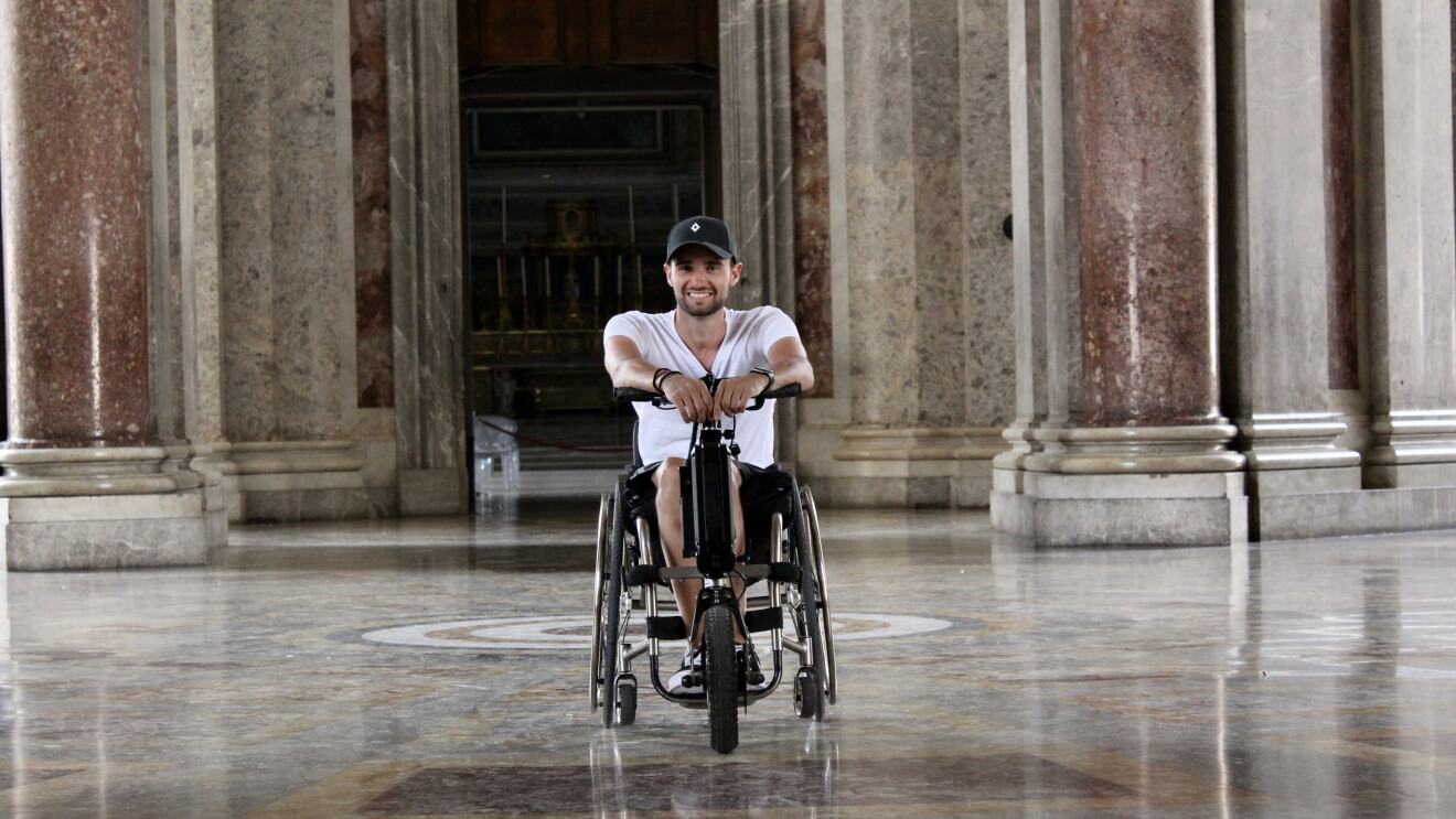 l'immagine mostra un giovane dipendente amazon in carrozzina nel suo tempo libero, al centro di una hall di un palazzo storico