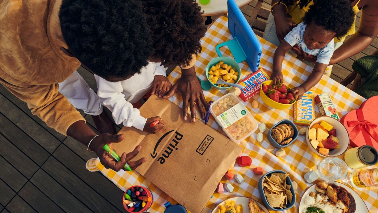 Family picnic with Prime delivery bag surrounded by colorful snacks