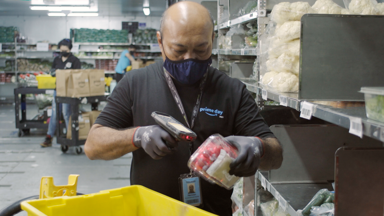 A man wearing a mask can be seen scanning a product with a cart in front of him