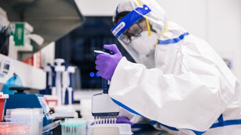 Two people in PPE look at lab samples.