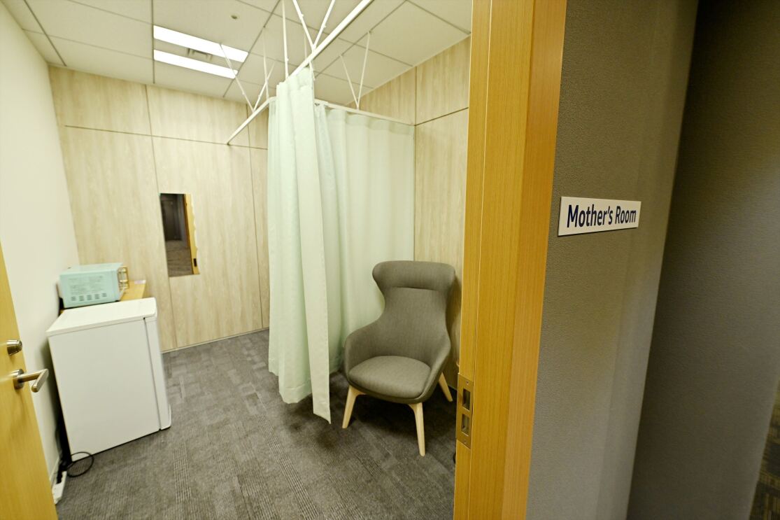 カーテンの仕切りがついている部屋に冷蔵庫と1人用のソファが置かれている