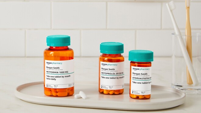 三个亚马逊药房药瓶放在一个白色托盘上,旁边是一个玻璃杯,里面有两把牙刷。