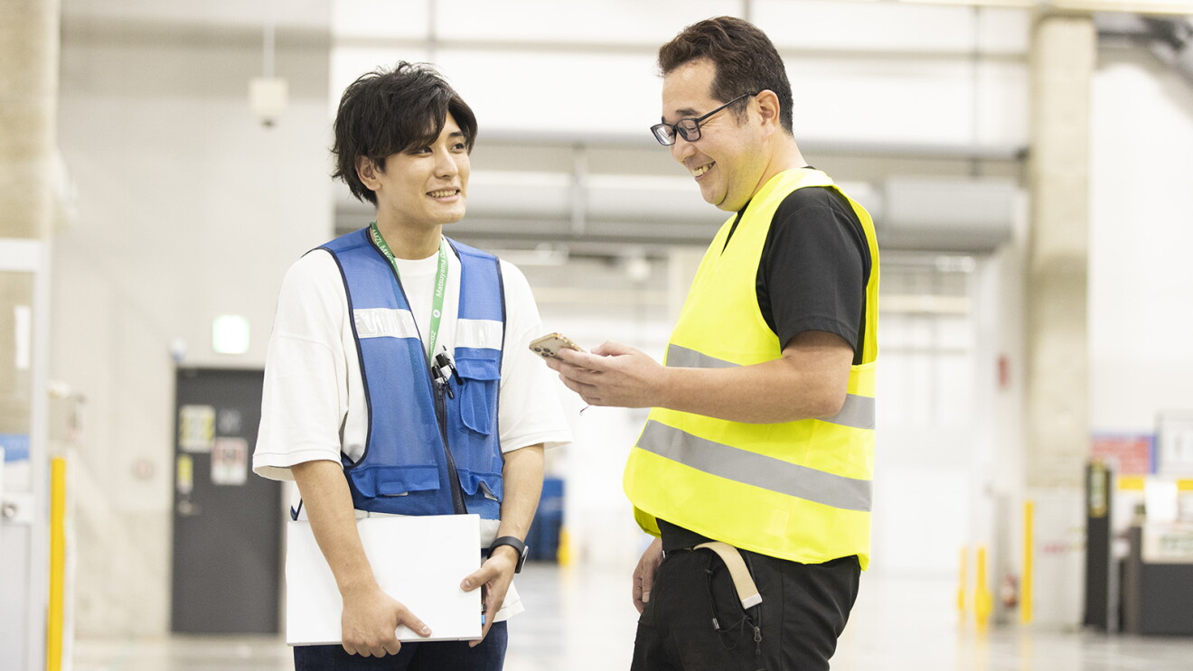 青いベストを着た男性（スタッフ）と談笑する男性（鈴木さん）