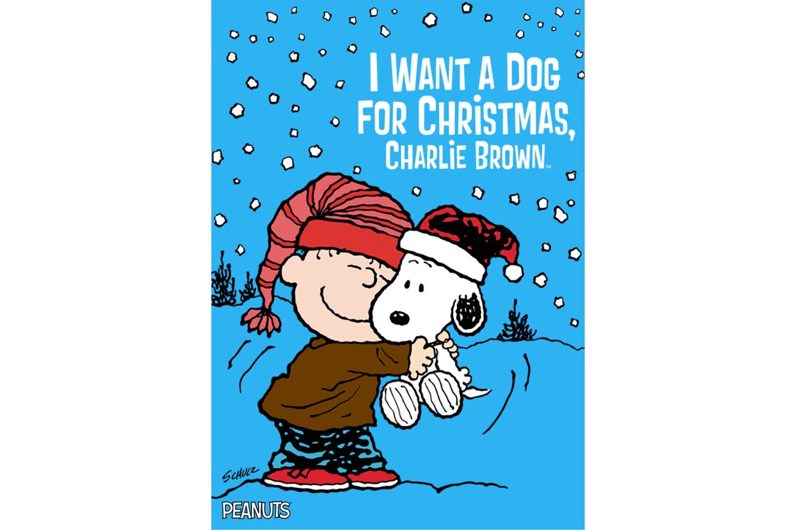 Linus, a character from the Peanuts cartoon, squeezes Snoopy, while standing outside. Snow falls lightly around them.