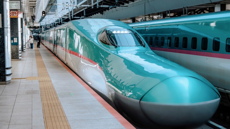 Turquoise Japanese bullet train at platform station