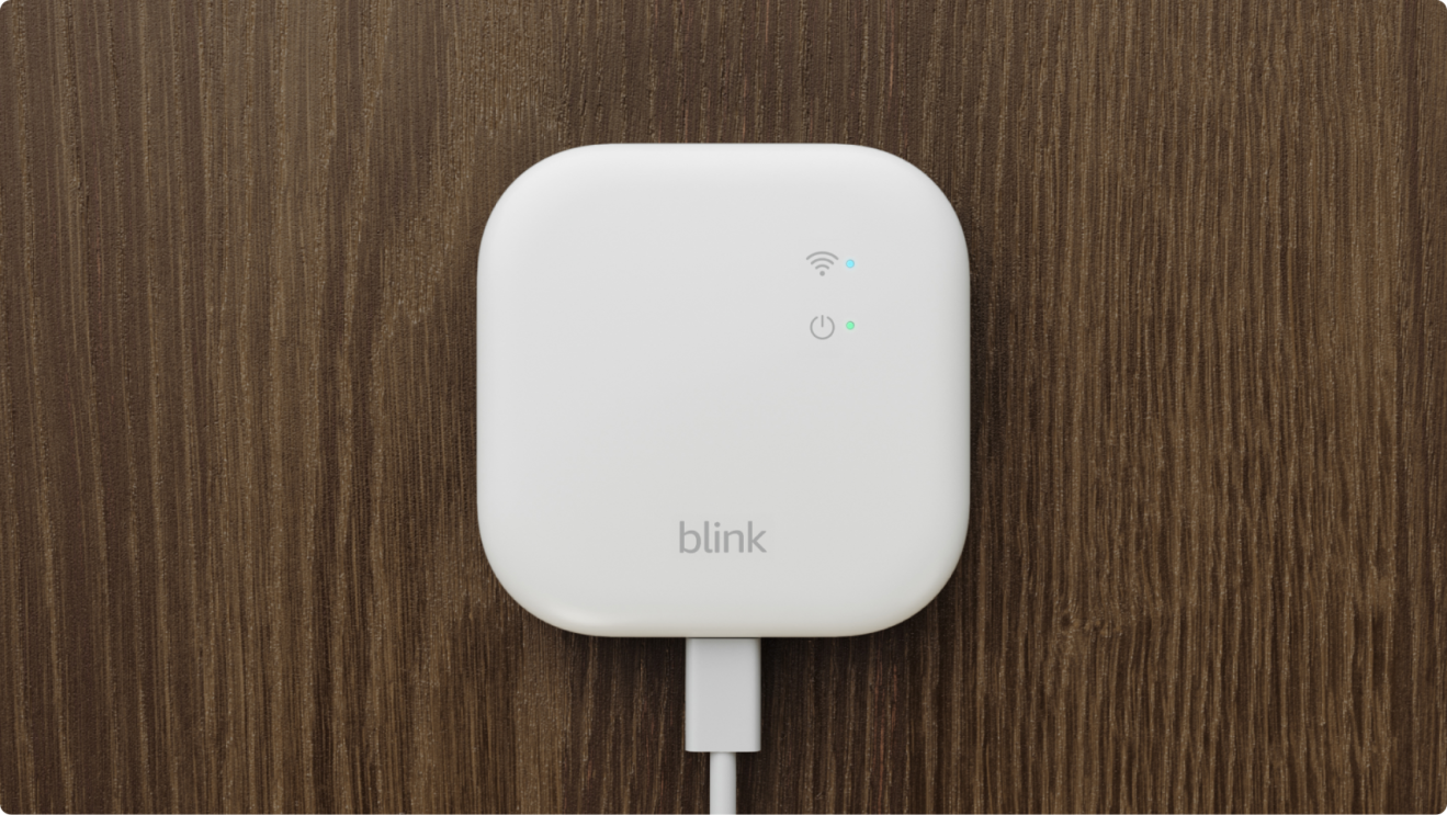 A white, square, Blink sync module mounted to a wooden wall