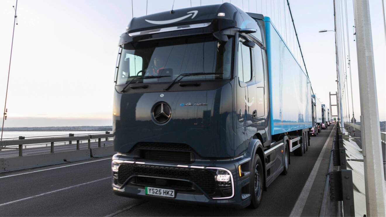 Electric Mercedes-Benz truck driving down highway, Amazon blue trailer attached