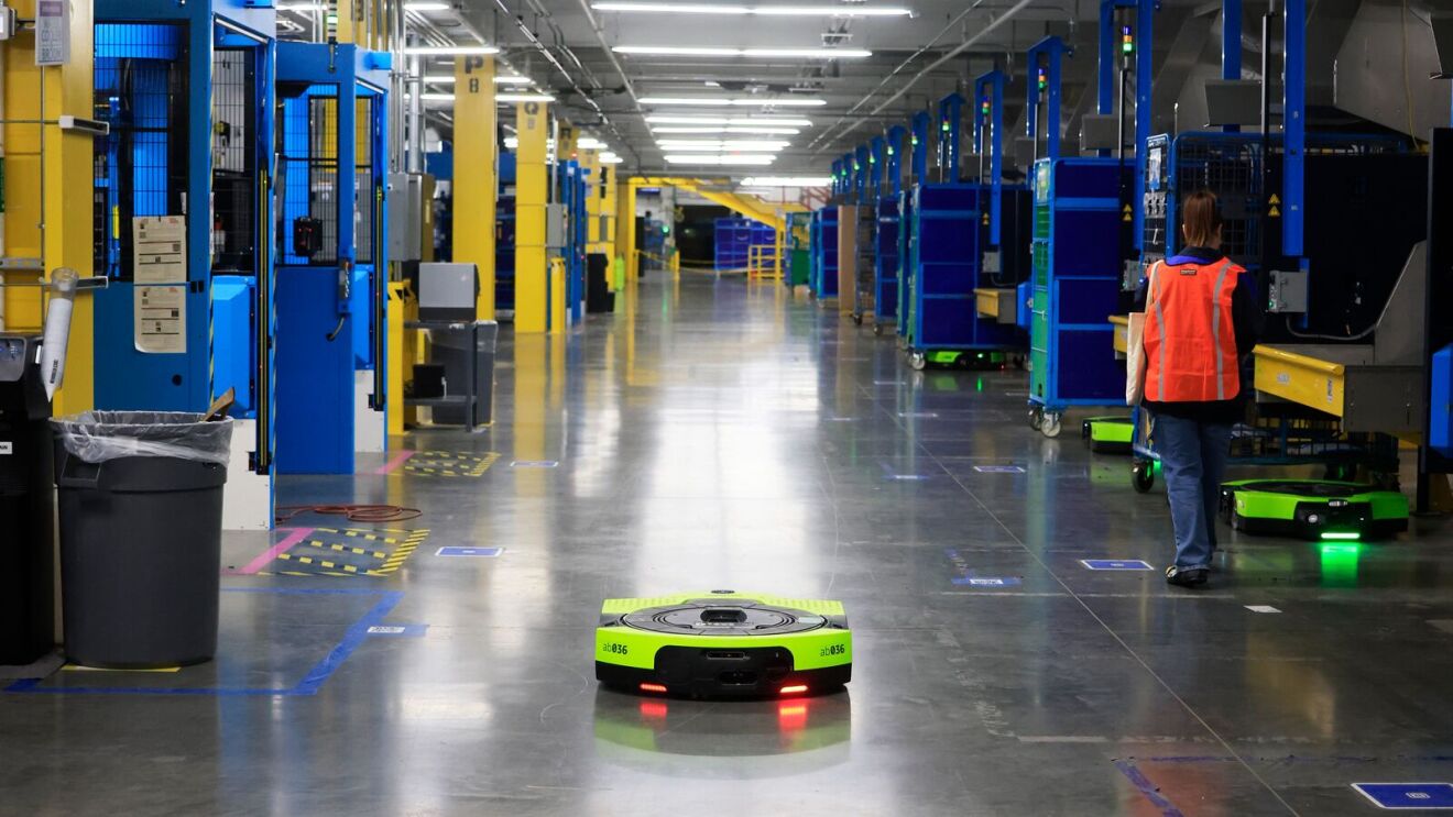 Amazon employee walks alongside an autonomous mobile robot
