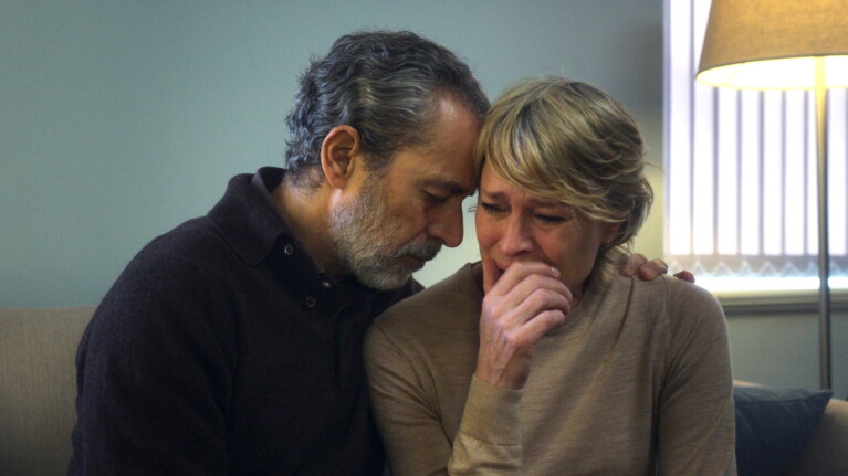 Couple in emotional embrace, woman crying with hand to mouth