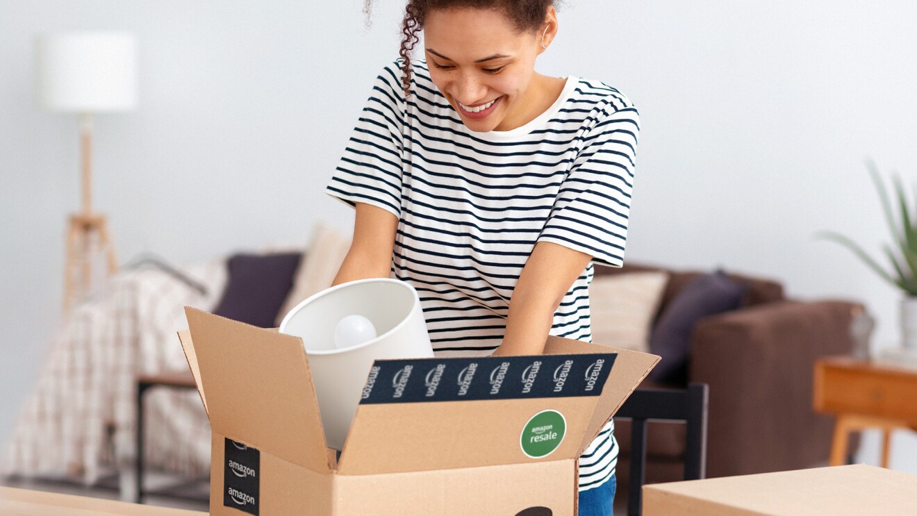 Woman smiling while unpacking Amazon box in living room
