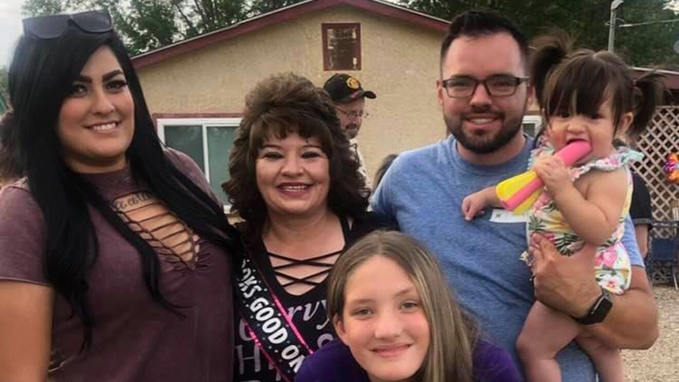 An image of a family standing together smiling for a photo at a get together. 