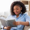 Une femme lit un livre gris chez-soi. 