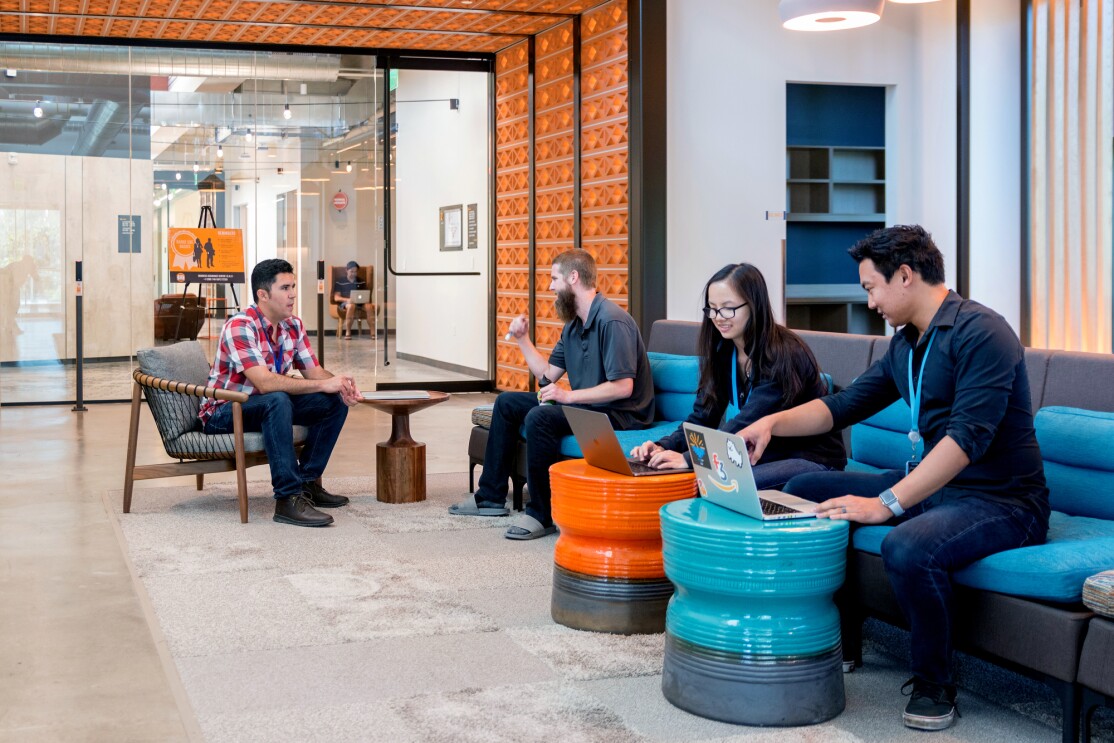 Amazon's San Diego tech hub, pairs of Amazonians sit in a common area, working on laptops and talking to one another.