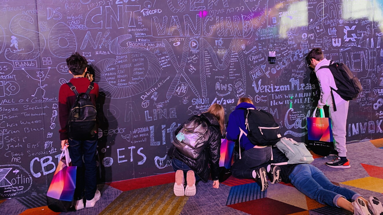 AWS GetIT students drawing on a giant blackboard which is filled with messages and doodles. 