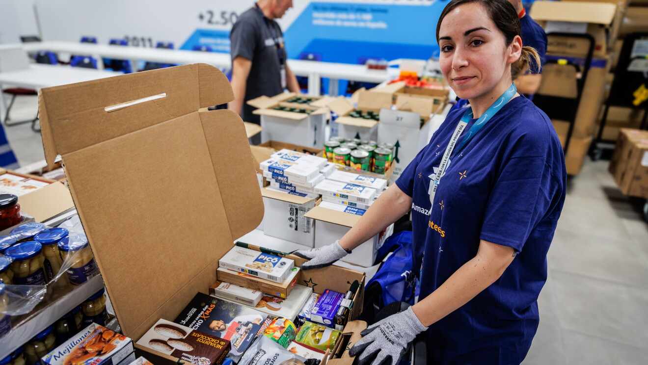 En una sala del centro logístico de MAD4 en San Fernando de Henares hay una voluntaria en primer plano preparando cestas. 