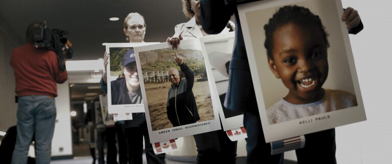 Personen, die bei einer Veranstaltung große Fotos von Personen hochhalten.