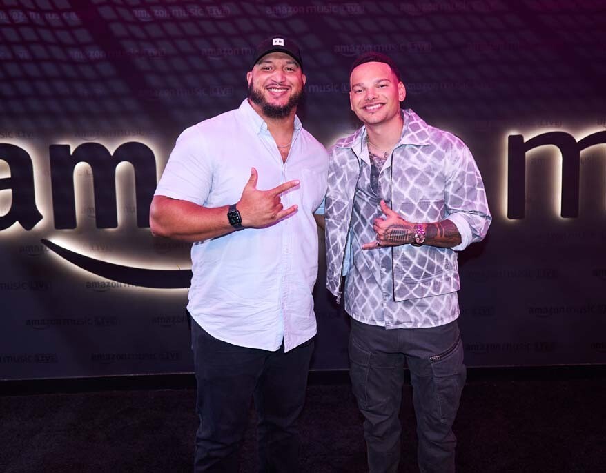 Martise Colston smiling for a photo with country artist Kane Brown on the "black" carpet with the Amazon Music logo behind them.