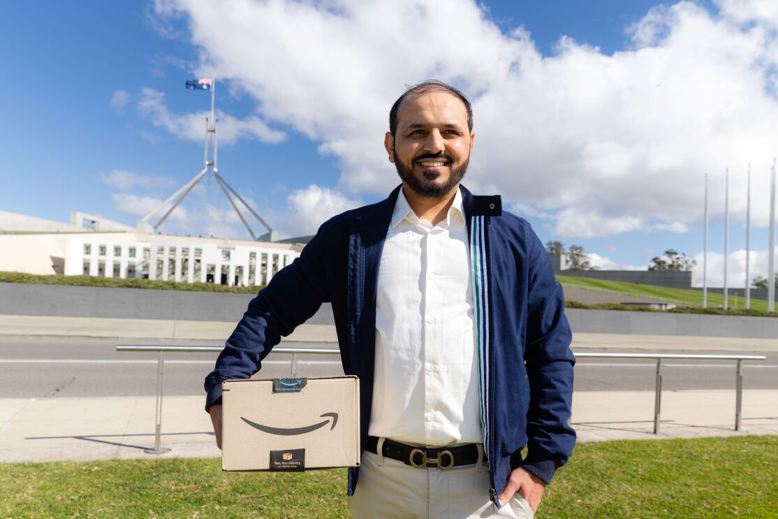 Majid Ali holding a prime box in front of Canberra parliament house