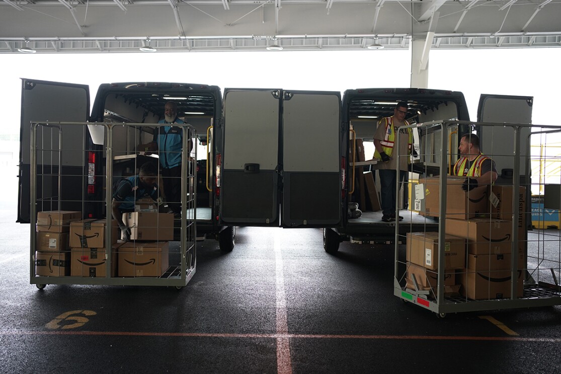 Volunteers and Amazon employees load up Amazon delivery vans with essential furniture and household products.