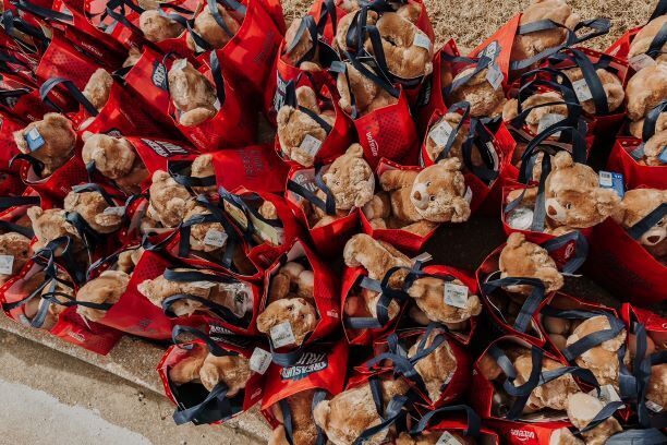 An image of red bags that have teddy bears and other fun items in them for donation. 