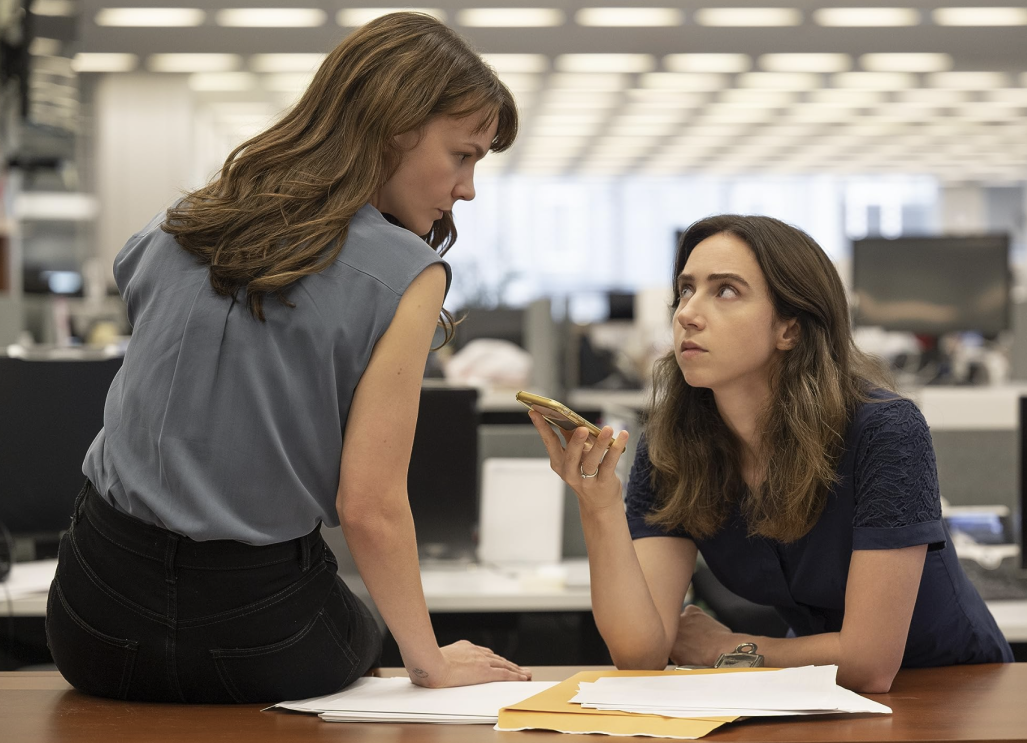 Two women sitting at a desk, engaged in a conversation and working together on an article.