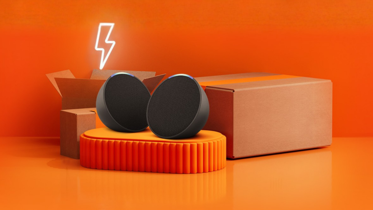 Amazon Echo Pop smart speakers on orange platform with cardboard boxes and neon lightning bolt
